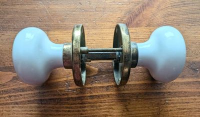 Vintage pair of white ceramic door knobs with brass back plates