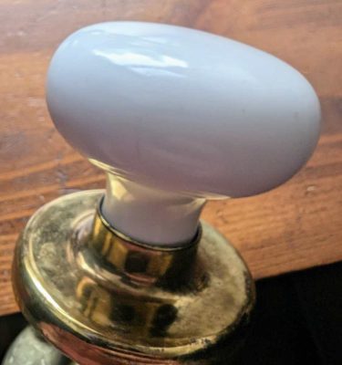 Vintage pair of white ceramic door knobs with brass back plates
